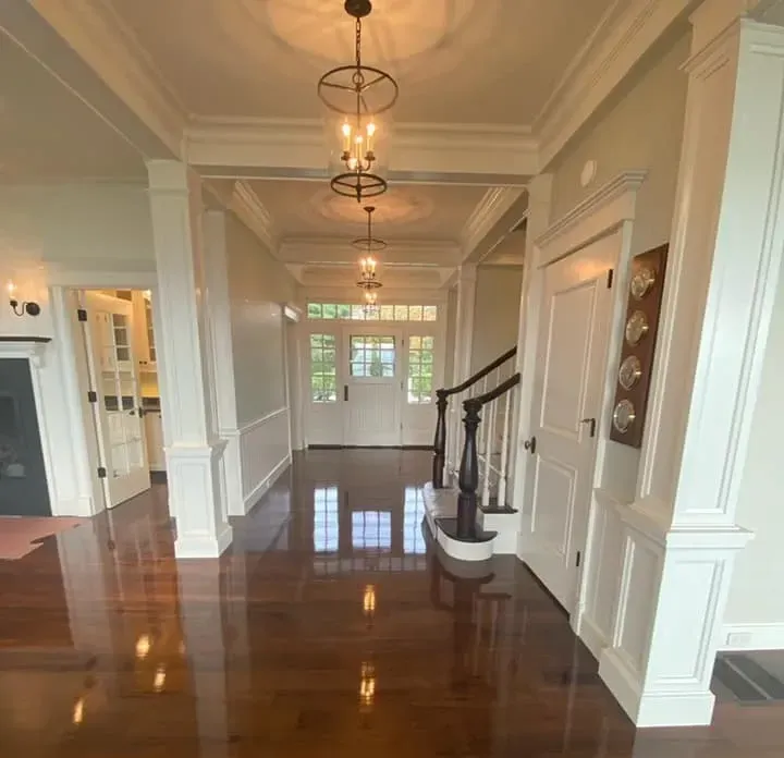 A hallway in a house with a staircase and chandeliers hanging from the ceiling