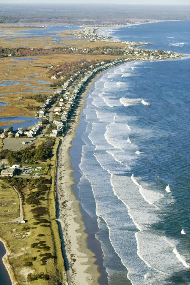 An aerial view of a beach with waves crashing on the shore