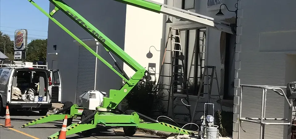 A green crane is parked in front of a building