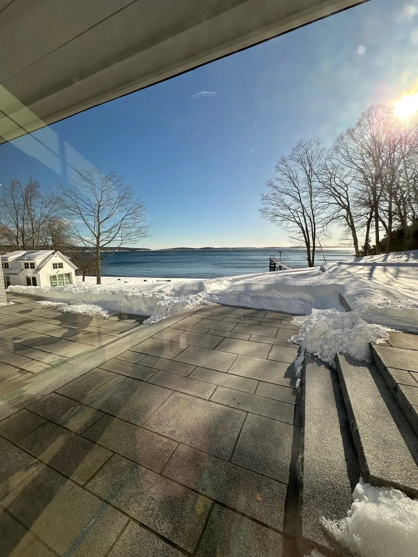A snowy patio with a view of a body of water.