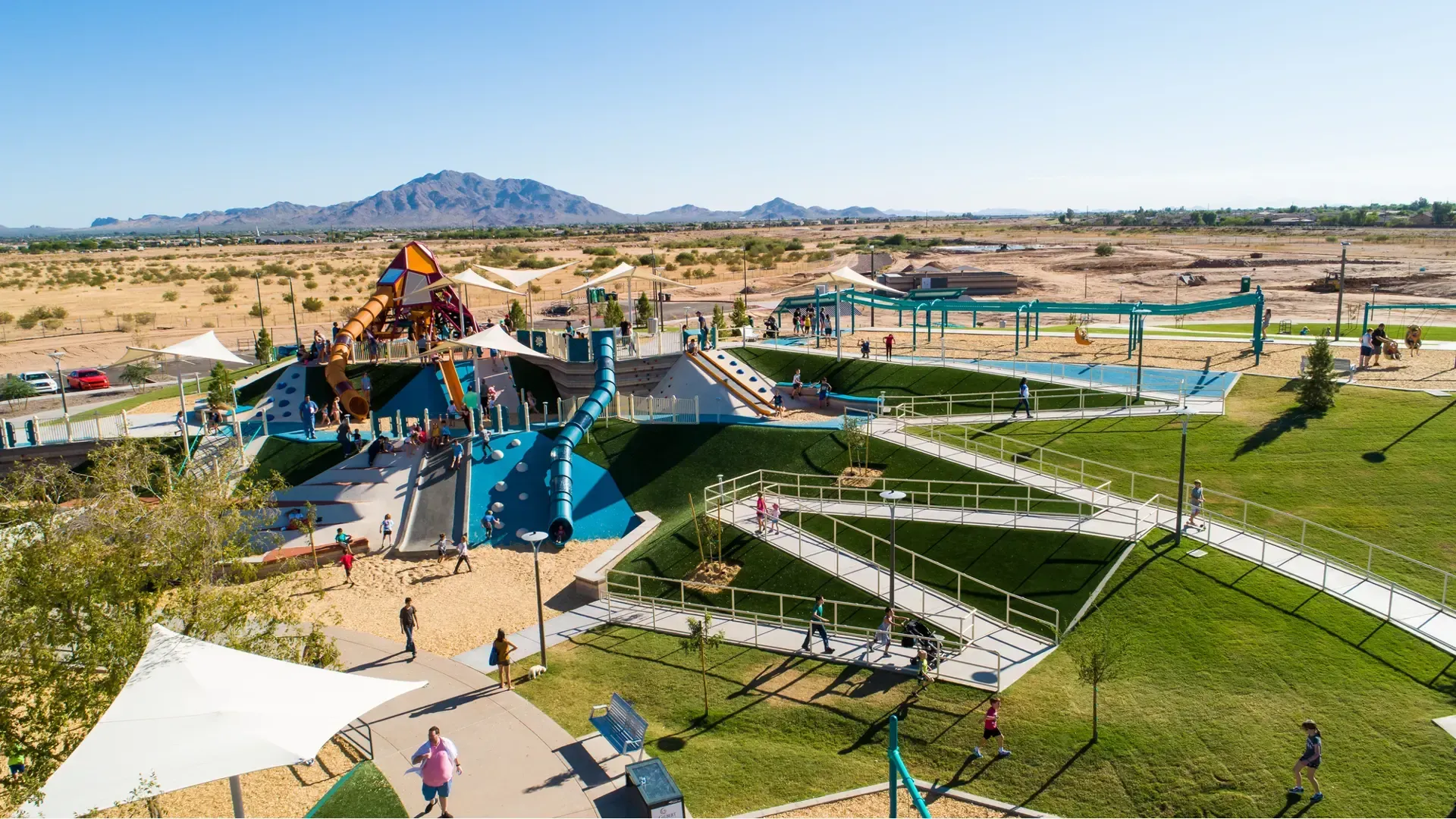 An aerial view of a park with a playground and mountains in the background.