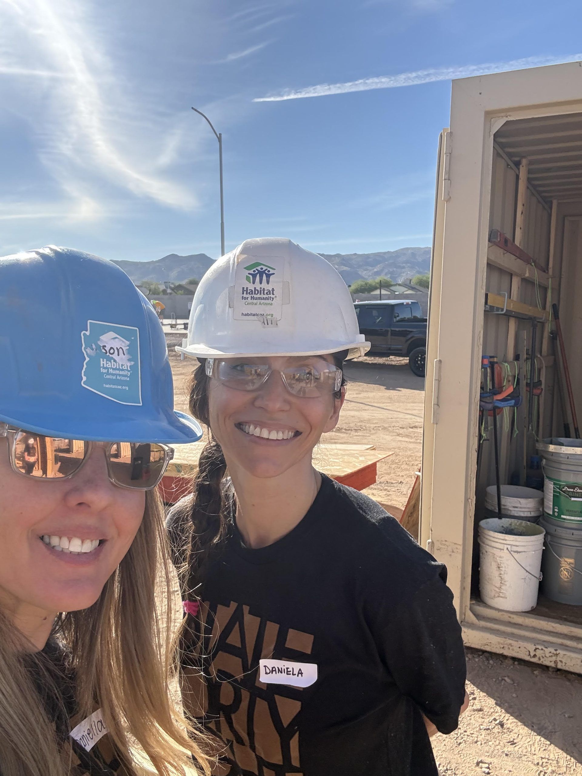 Two women wearing hard hats and safety glasses are posing for a picture.