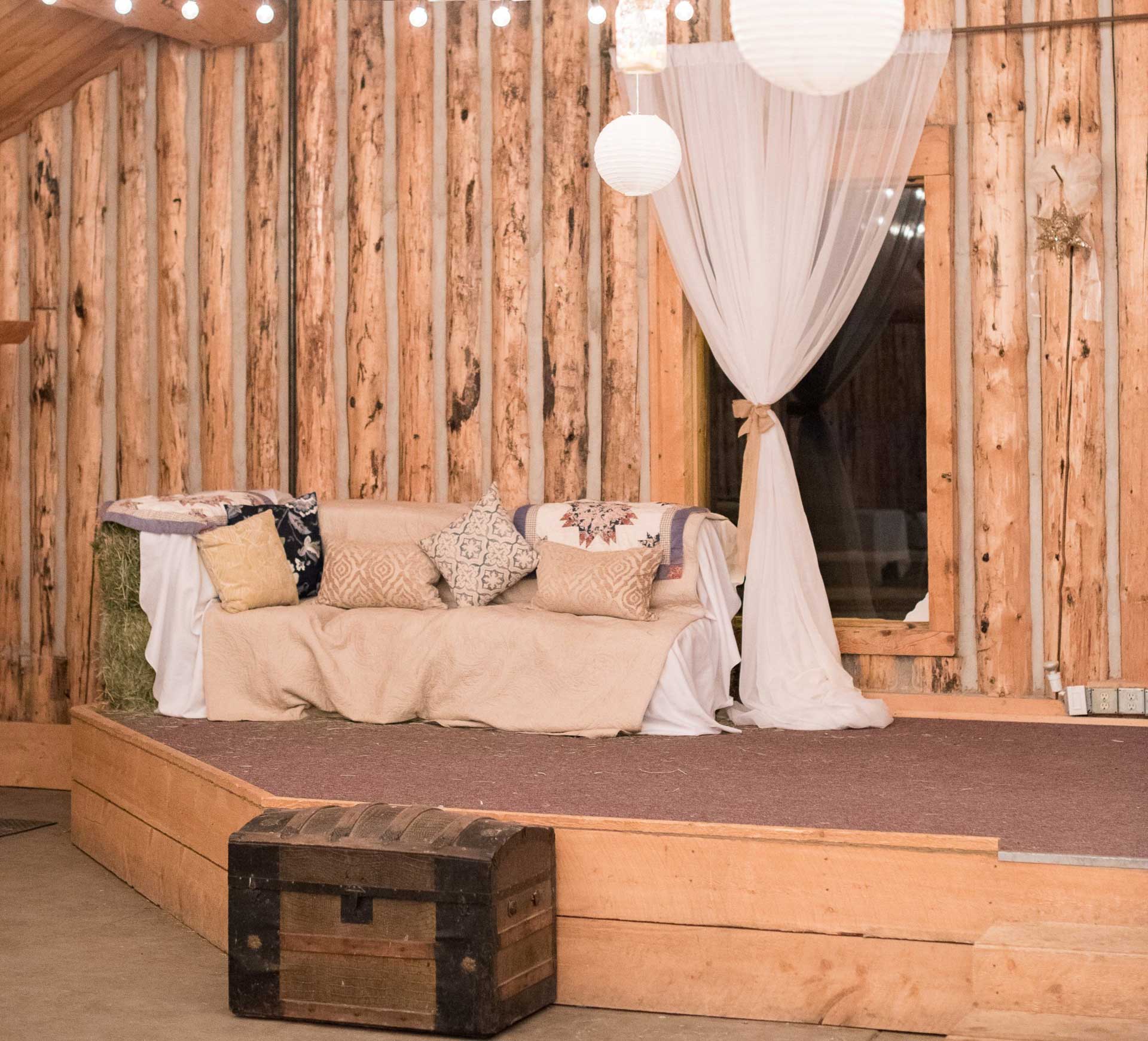 barn interior for wedding with cozy sofa, chest for rustic look and paper lanterns