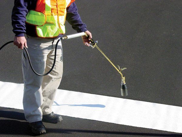 Man Spraying White Paint on The Road — Pensacola, FL — Emerald Coast Striping