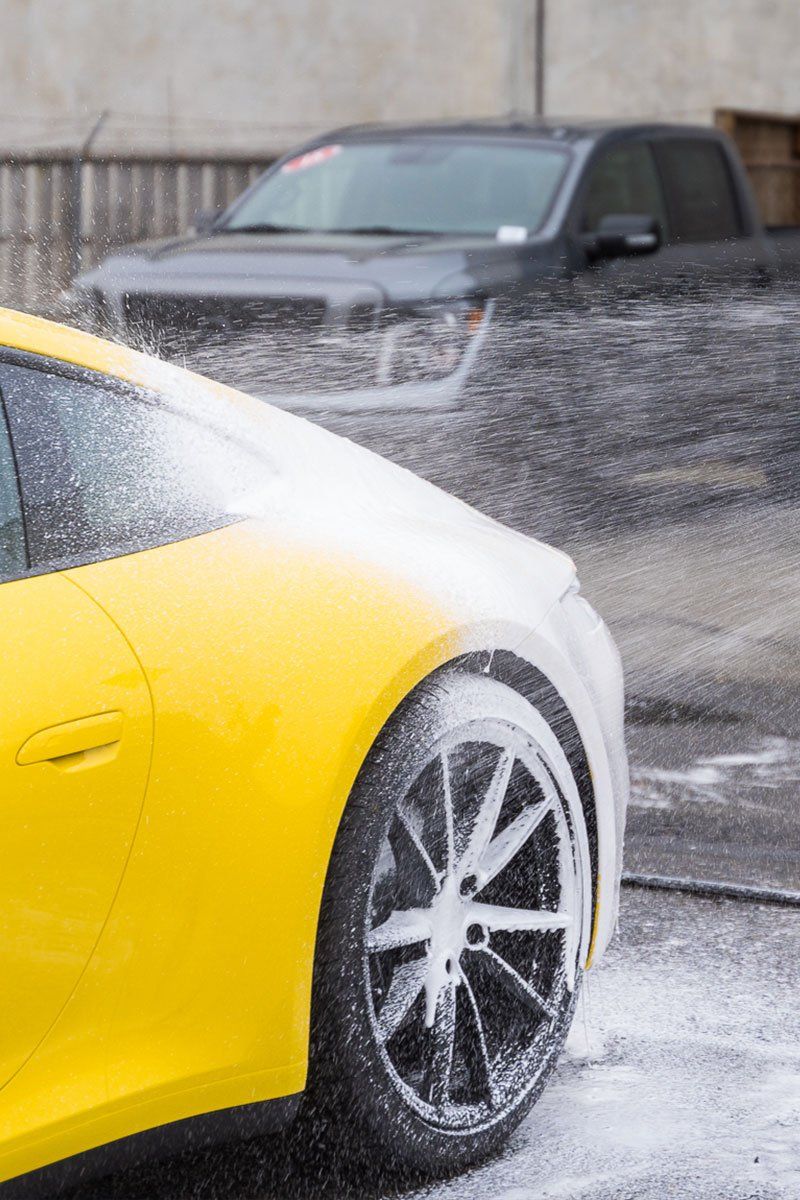 A yellow sports car is being washed with foam.