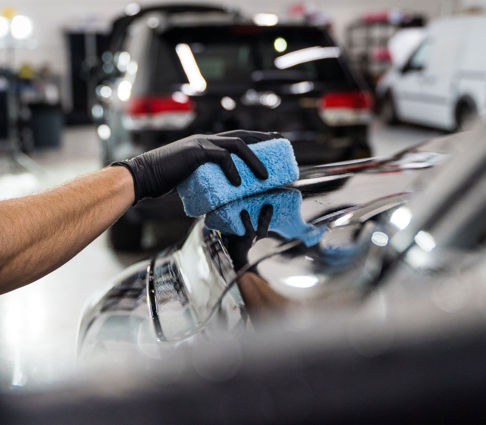 A person is cleaning a car with a blue sponge.