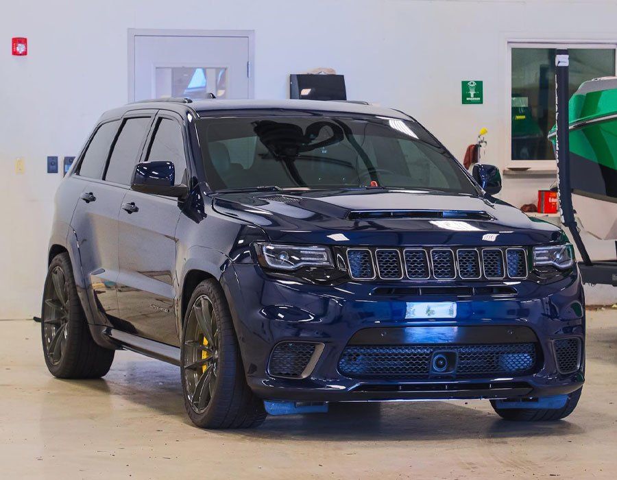 A black jeep grand cherokee is parked in a garage next to a boat.