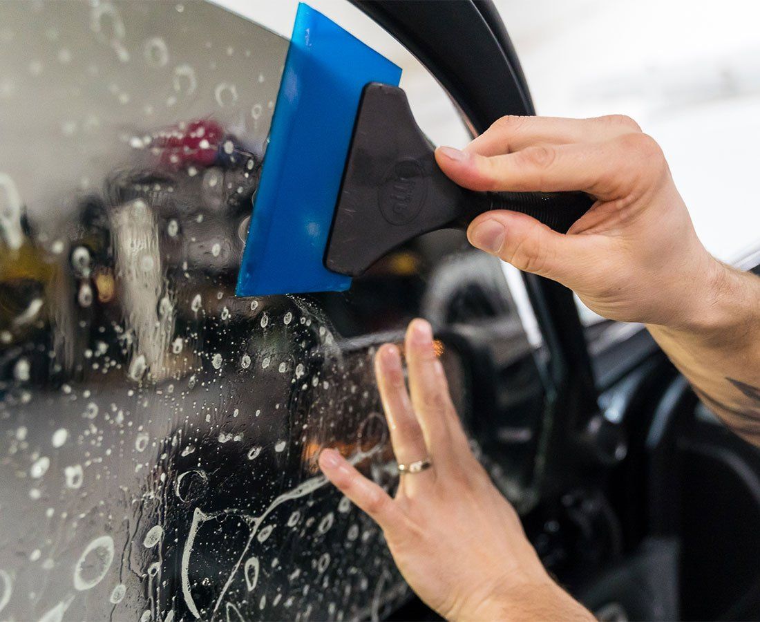 A person is applying window tinting to a car window.