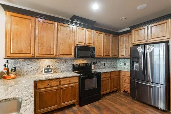 A kitchen with wooden cabinets , stainless steel appliances , and granite counter tops.