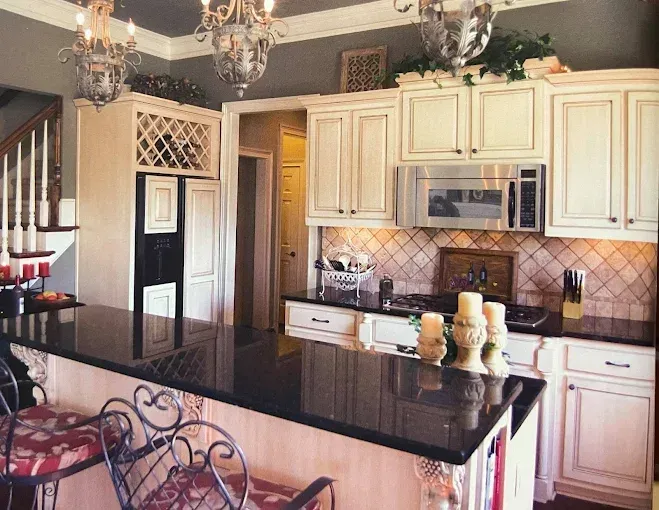 A kitchen with white cabinets and black counter tops