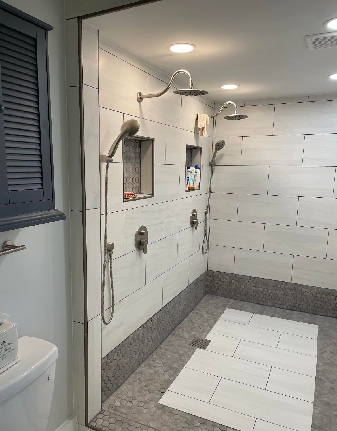 A bathroom with two showers and a toilet.