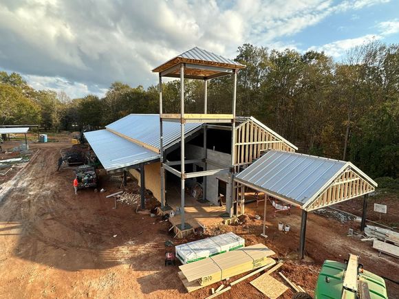 An aerial view of a building under construction in the middle of a dirt field.