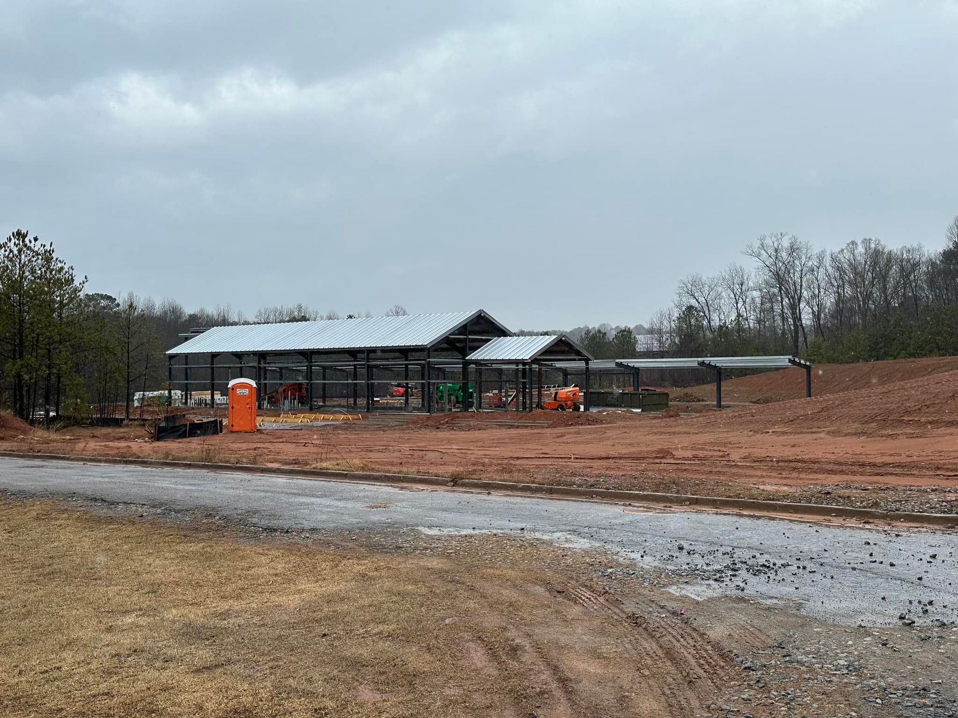 A large building is being built in the middle of a dirt field.