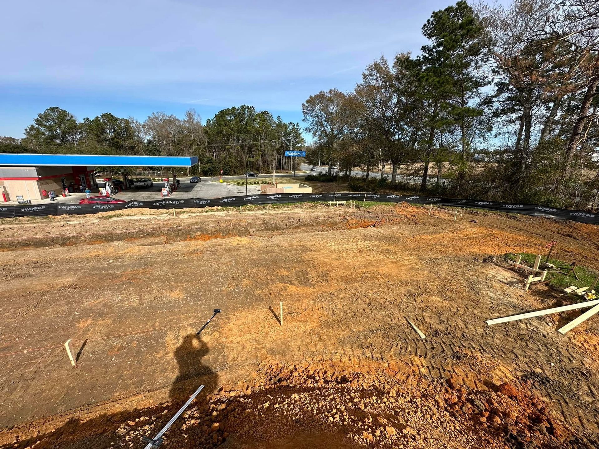 A large dirt field with a gas station in the background.