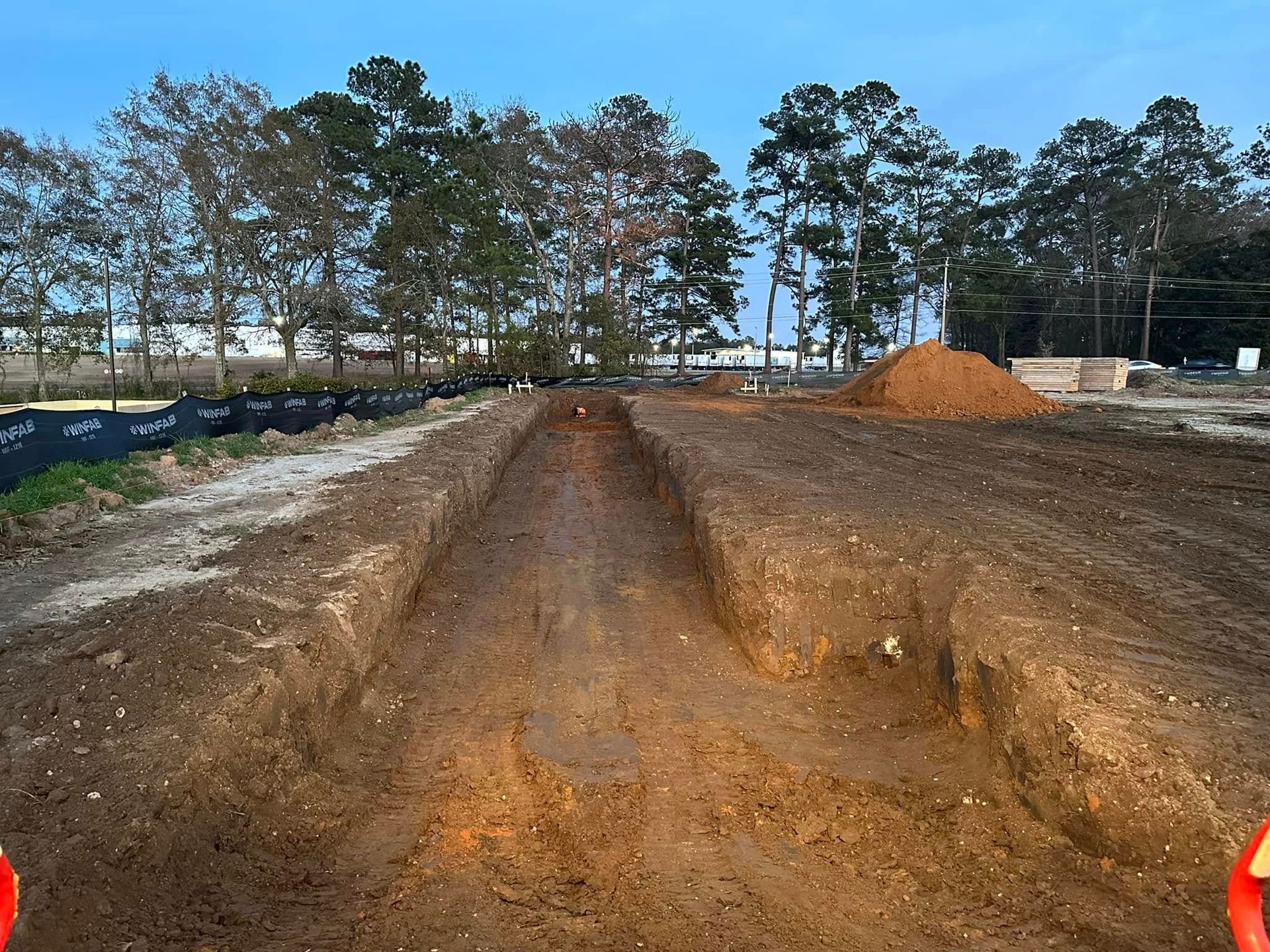 A construction site with a lot of dirt and trees in the background