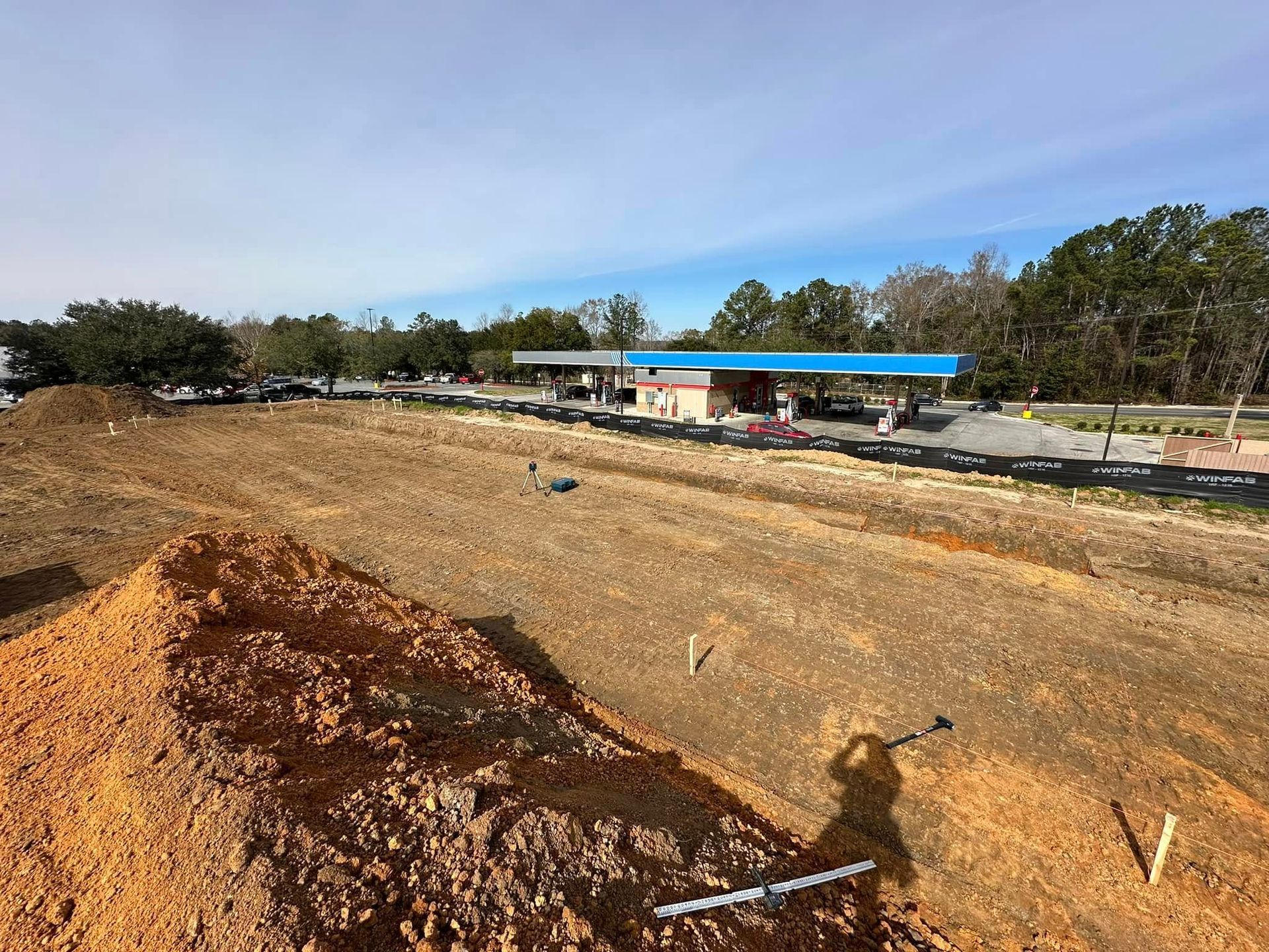 A large pile of dirt is sitting in front of a gas station.