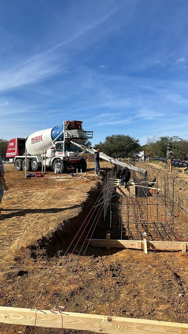 A concrete mixer truck is pouring concrete into a hole in the ground.