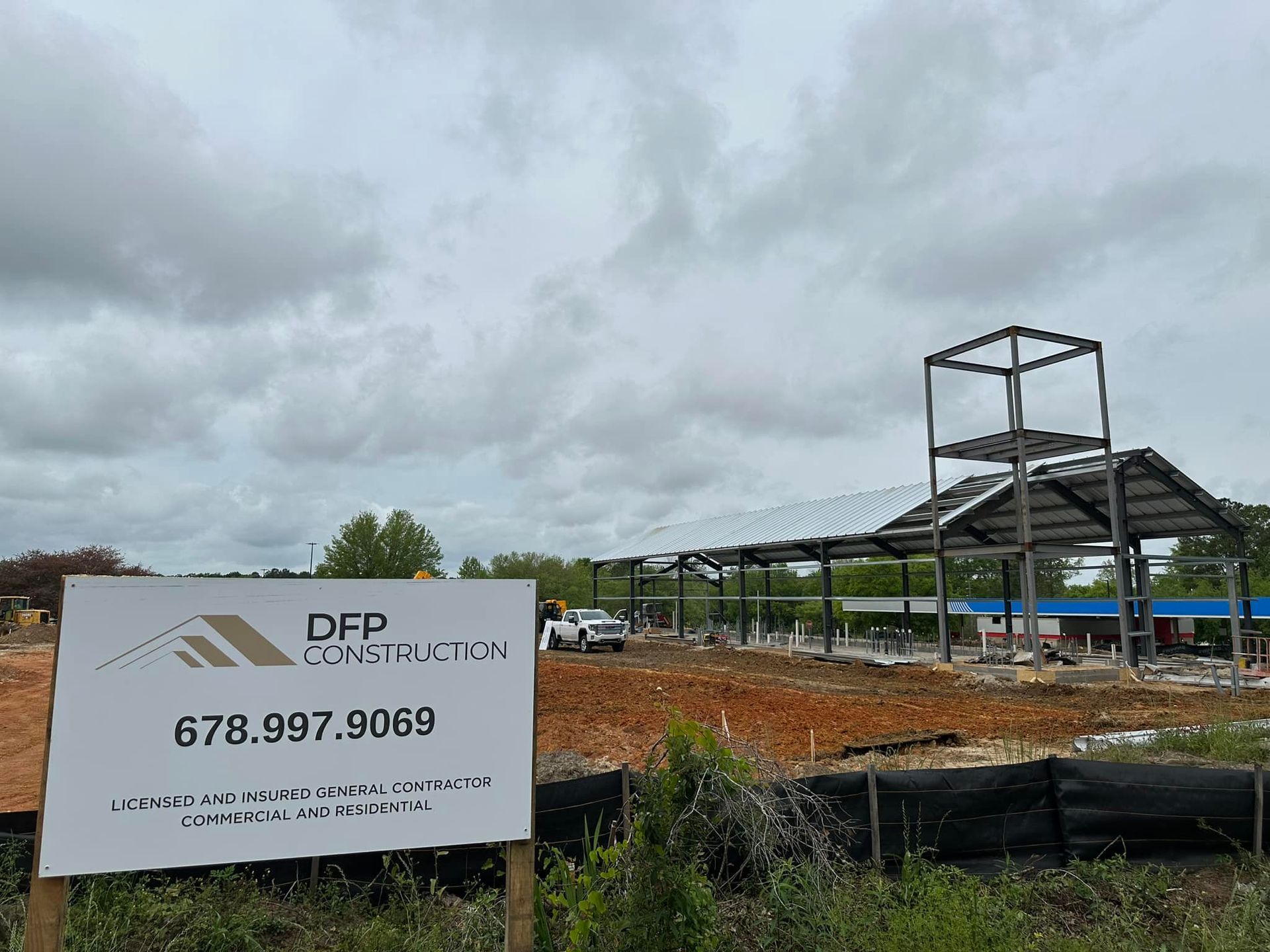 A construction site with a sign in the foreground and a building in the background.