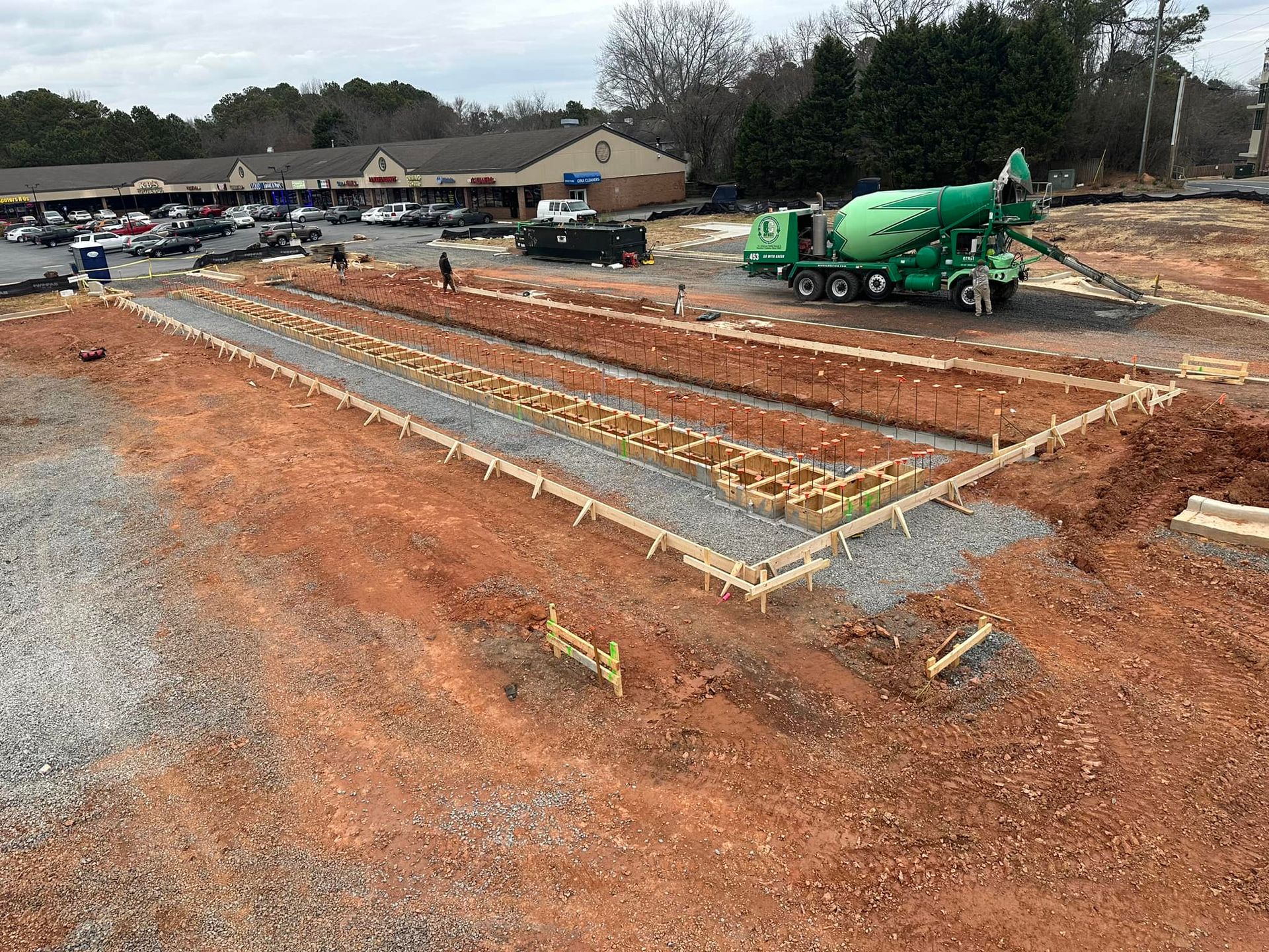 A green concrete mixer is pouring concrete on a construction site.