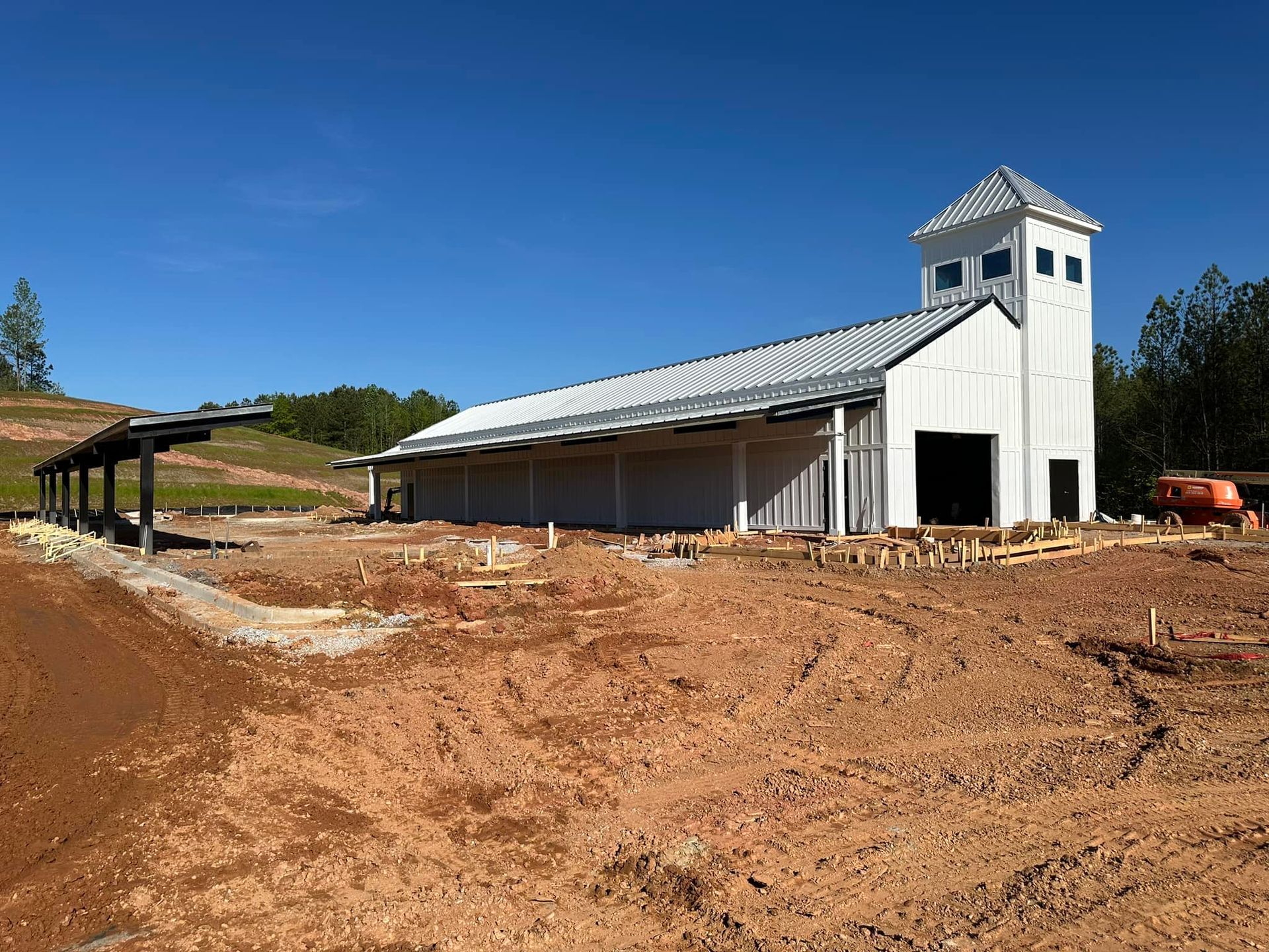 A large white building is being built in the middle of a dirt field.