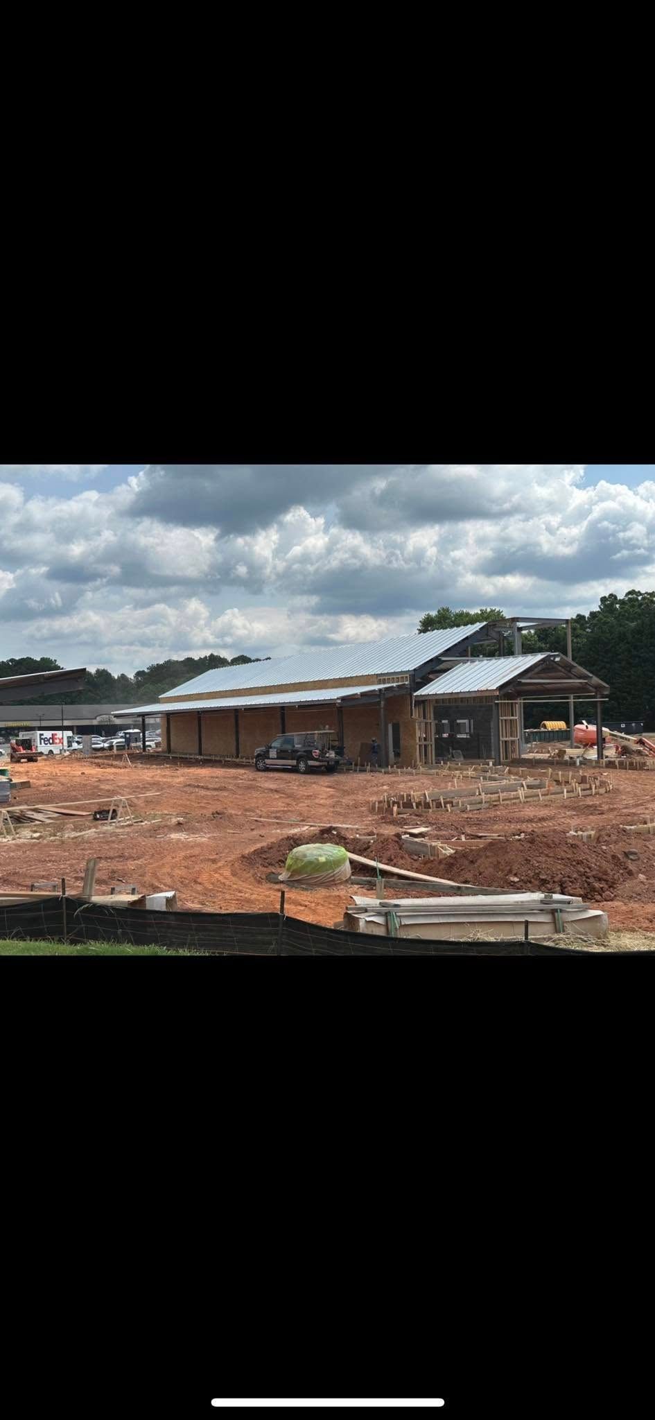 A large building is being built in the middle of a dirt field.