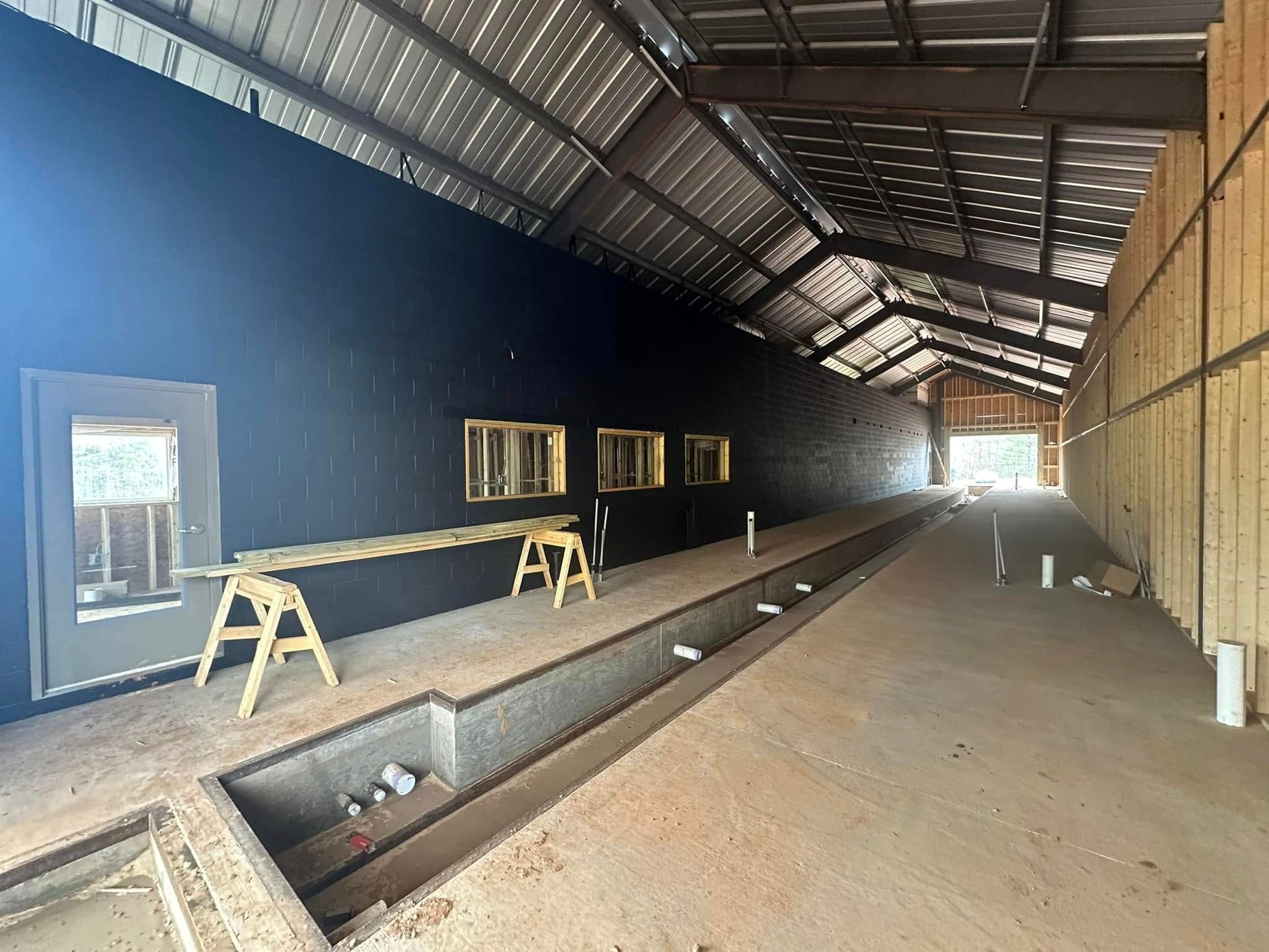 A large empty building with a lot of windows and a drain in the middle.