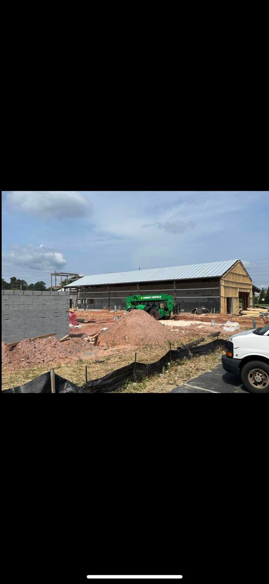A white truck is parked in front of a building under construction.