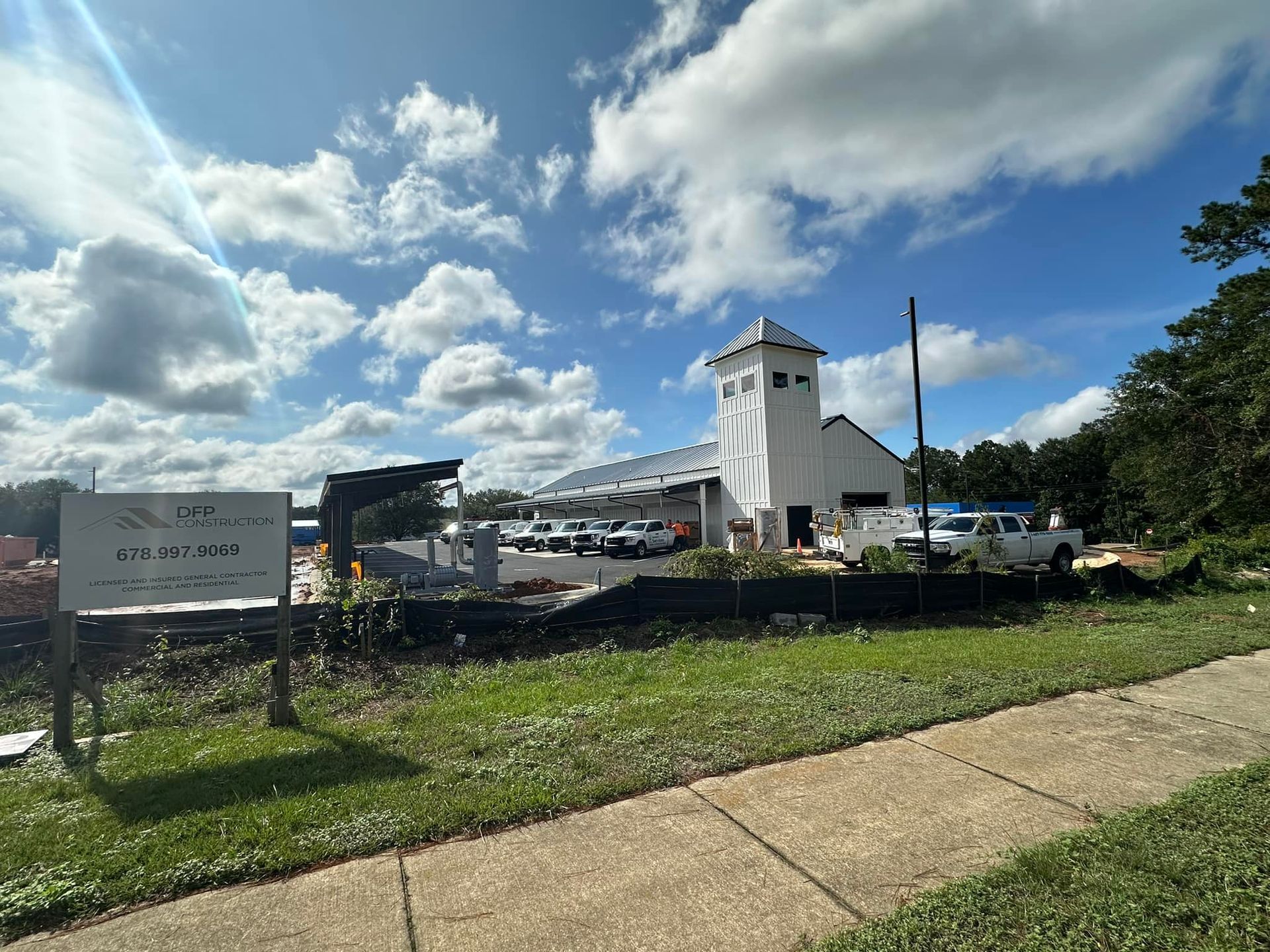 A white building is sitting on top of a lush green field next to a sidewalk.