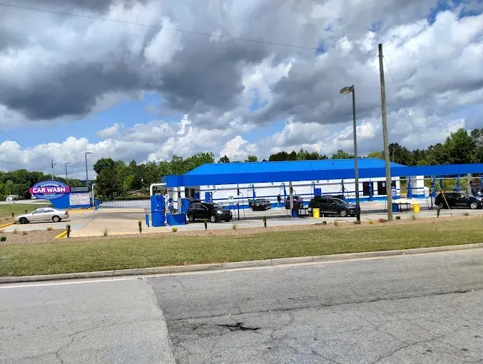 A car wash with cars parked in front of it on a cloudy day.