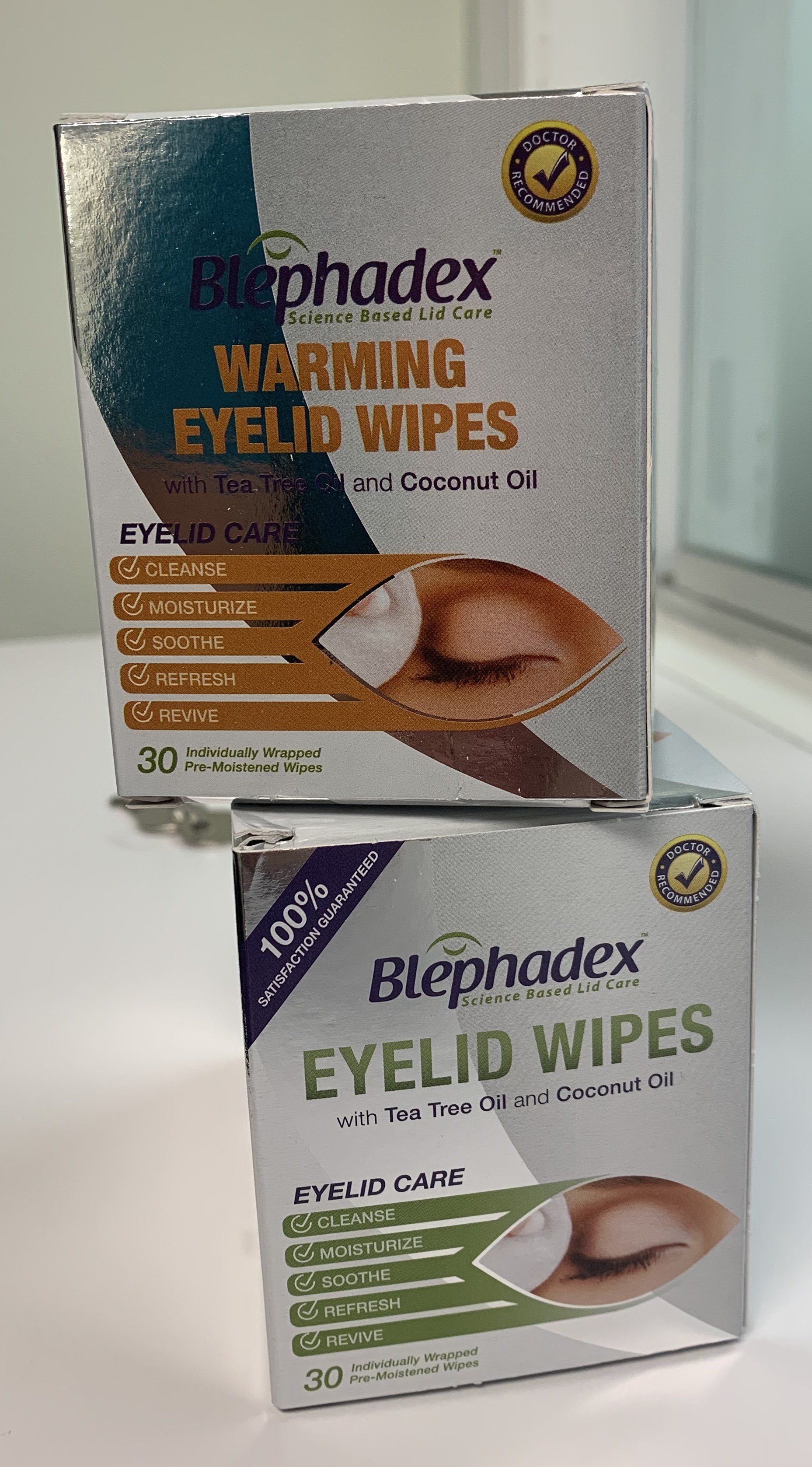 Two boxes of Blephadex eyelid wipes stacked. One is warming with a teal top, the other is purple top.