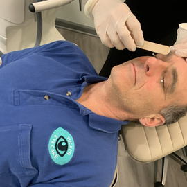 Man receiving eye care, eye exam. Eye doctor using stick to check eyelid.