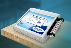 A white medical device (MiBo Thermoflo) with a screen sits on a wooden surface, with a blue background.