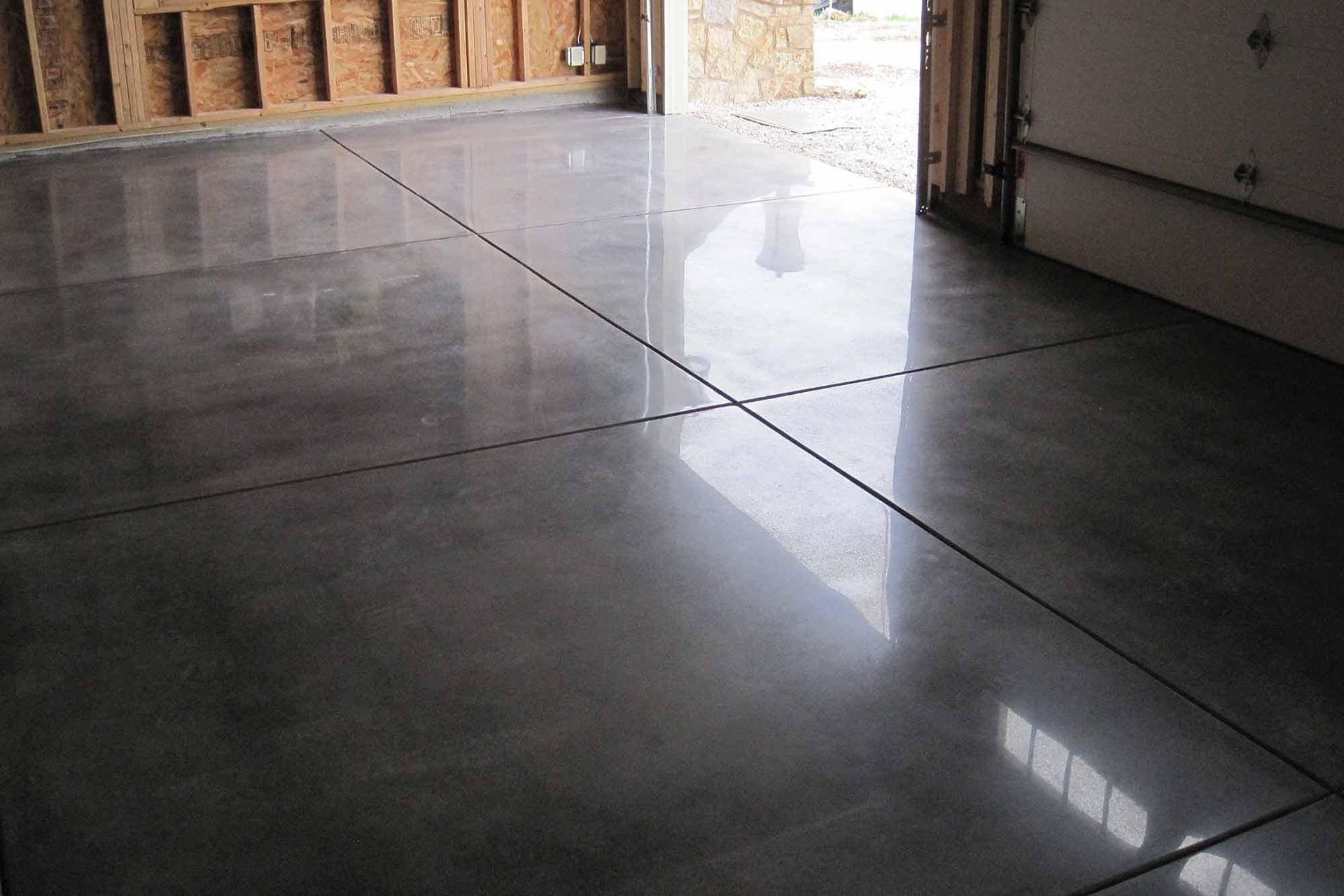 Empty garage with shiny gray concrete floor and light coming through the open door