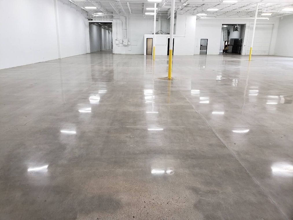 Empty polished warehouse or garage with white walls, concrete floor, and yellow safety posts