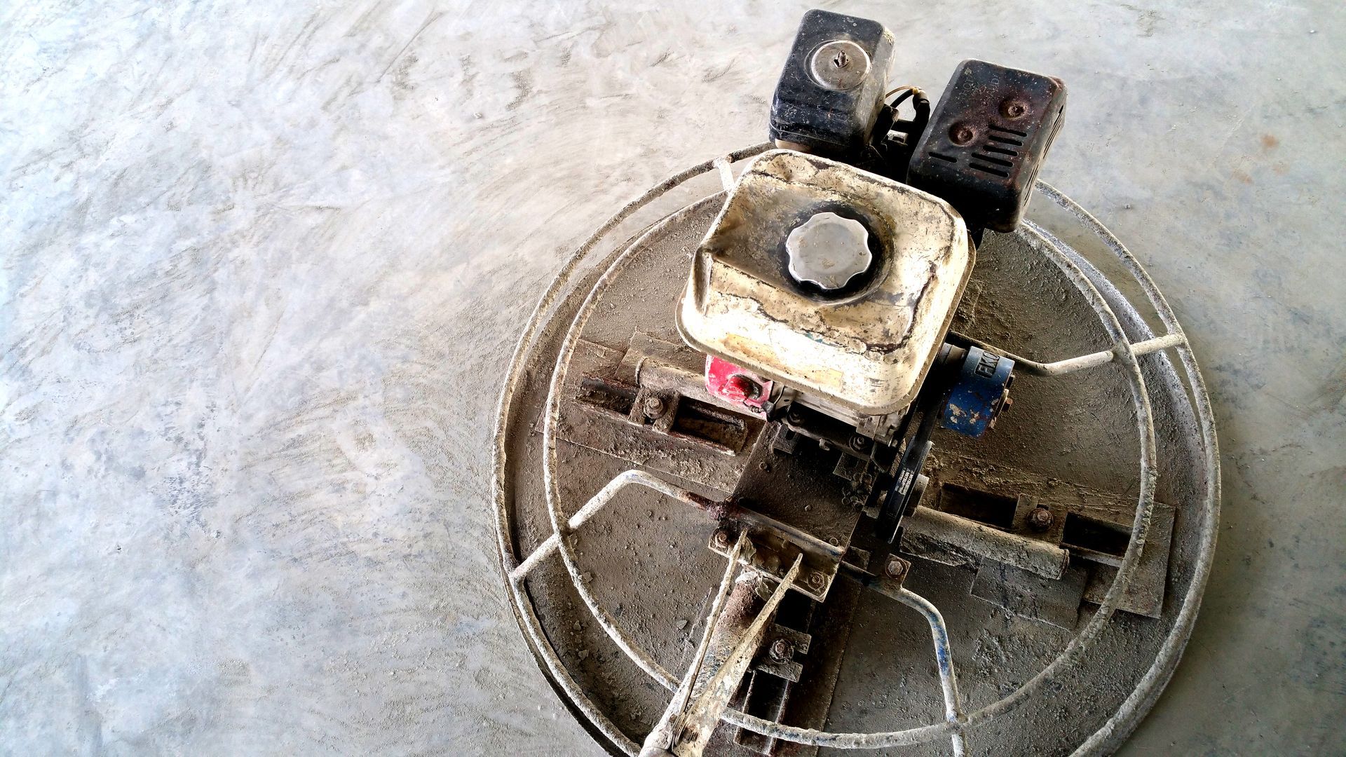 Small robot on a circular metal frame, with wires and two black wheel-like parts on a concrete floor