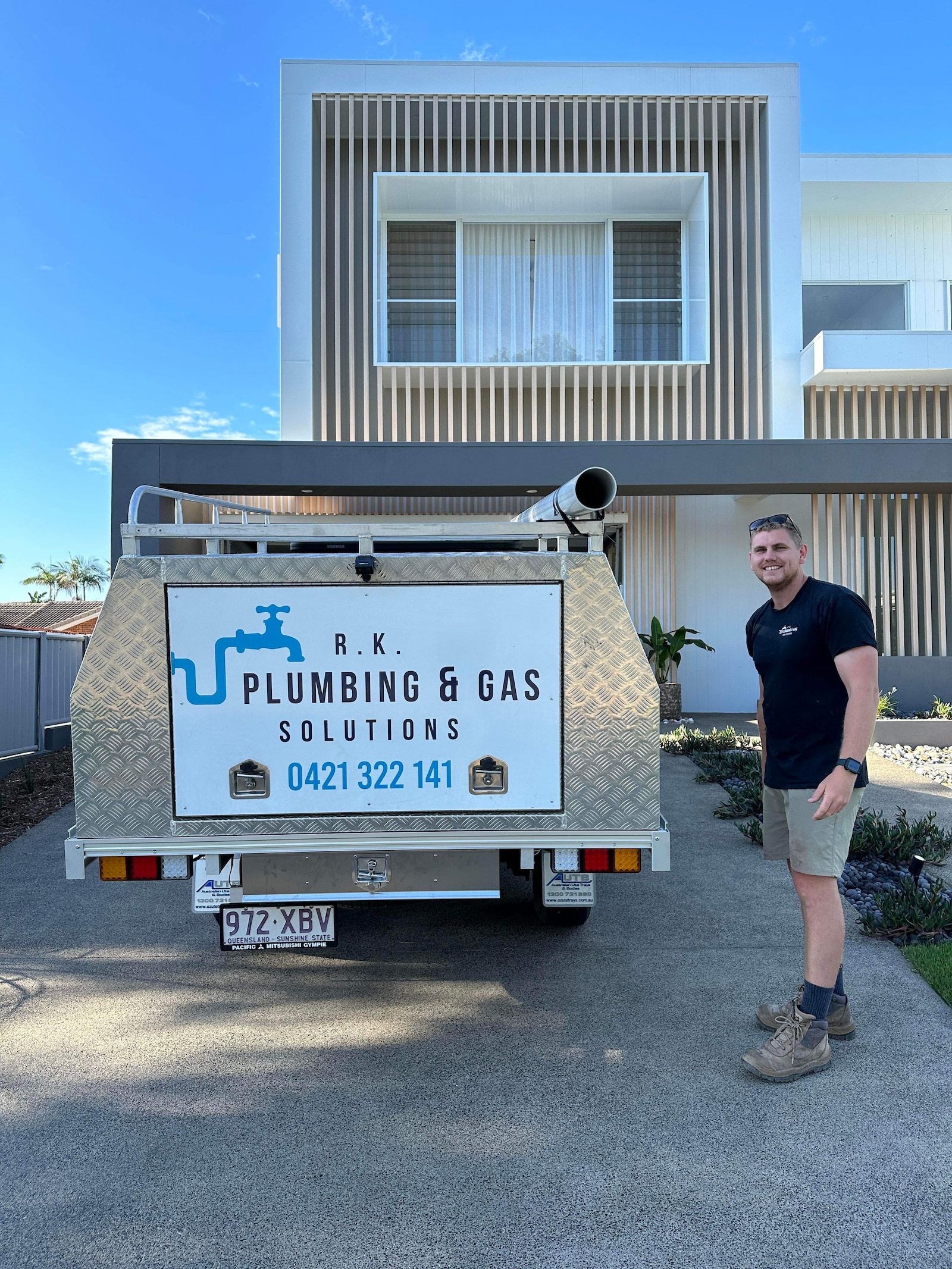 A Man is Standing Next to a Truck With a Helmet on His Back — R.K. Plumbing & Gas In Bli Bli, QLD
