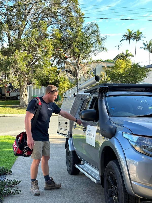 A Man is Standing Next to a Truck With a Helmet on His Back — R.K. Plumbing & Gas In Bli Bli, QLD