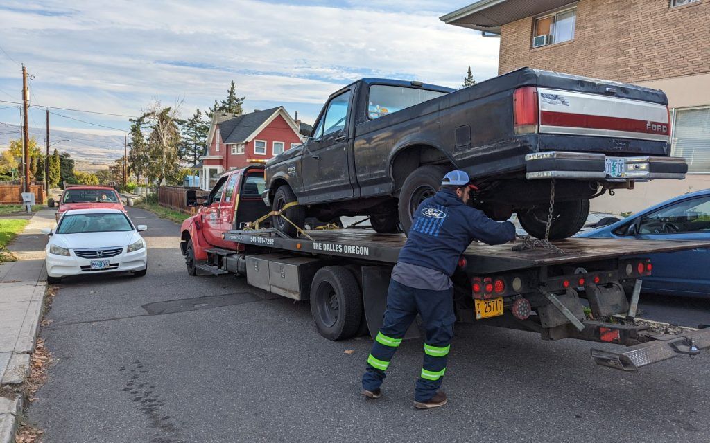 A man is loading a truck on a tow truck.