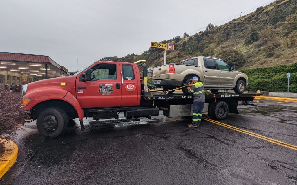 A tow truck is towing a car in a parking lot.