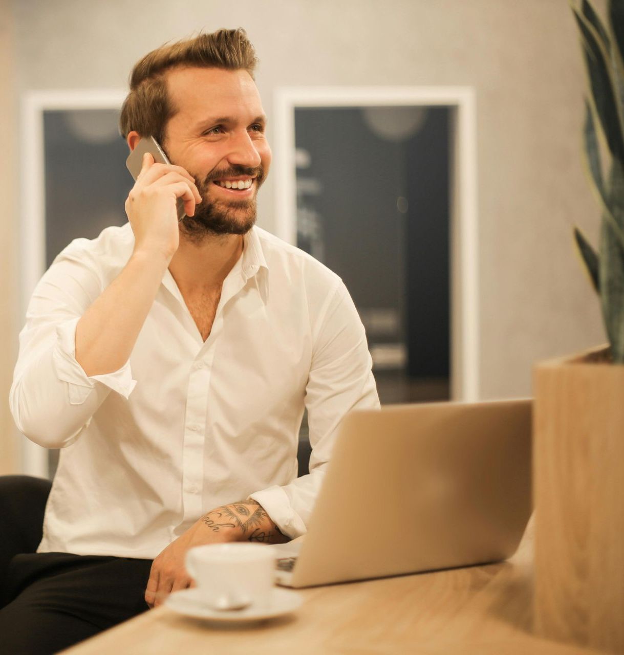 A man is talking on a cell phone while sitting in front of a laptop