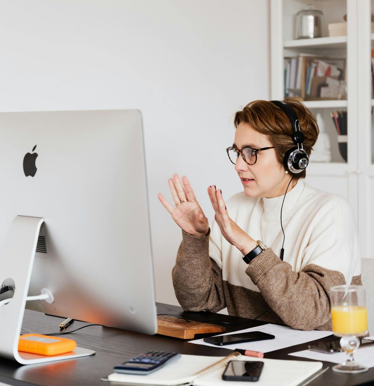 A woman wearing headphones is sitting in front of an apple computer