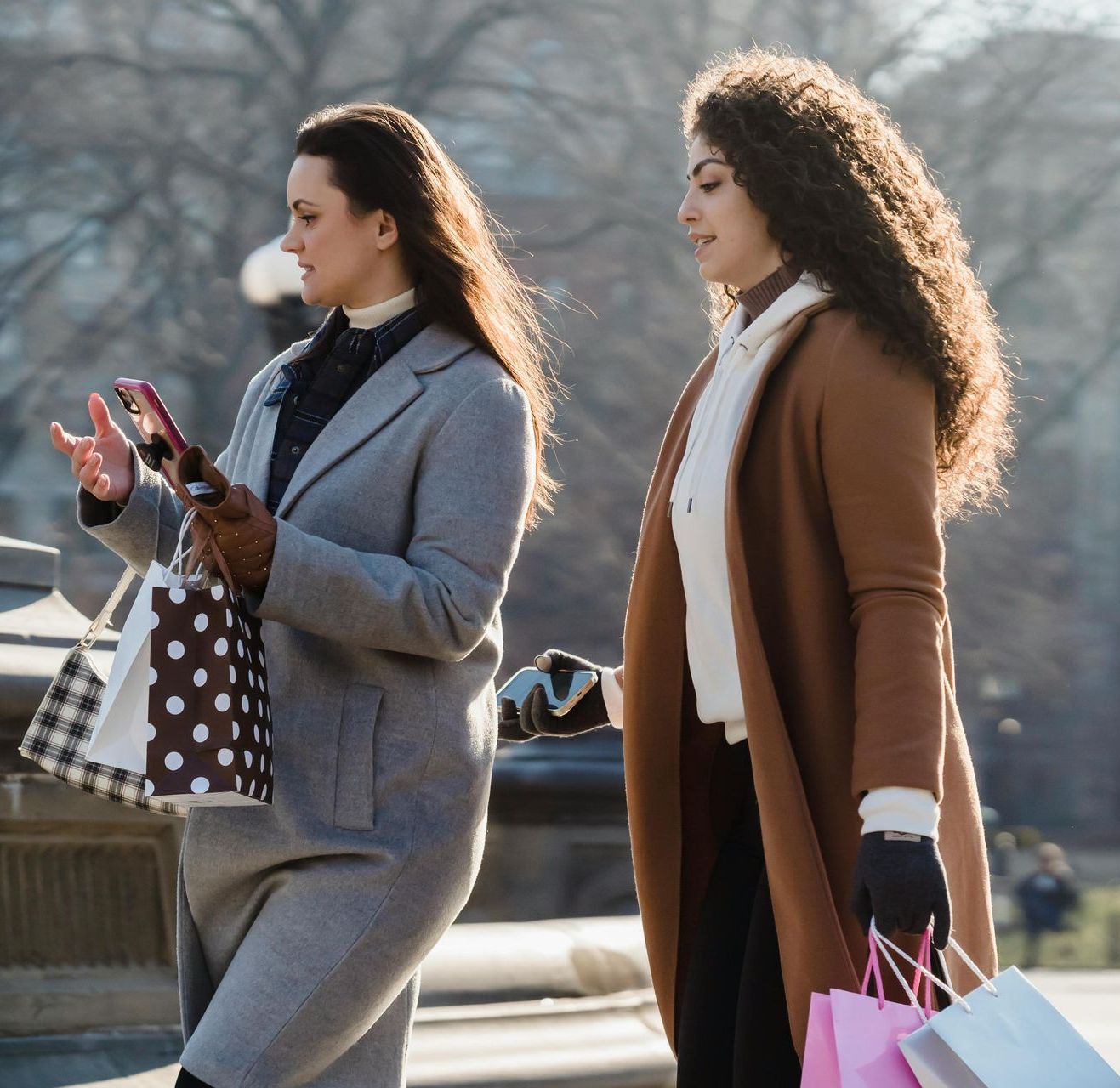 Two women are walking down the street and one is looking at her phone