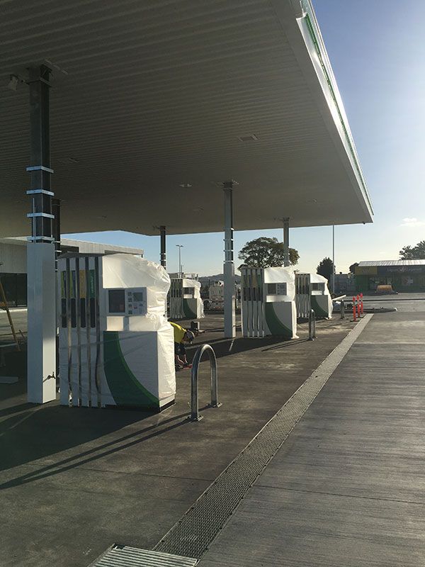 A row of gas pumps under a canopy at a gas station