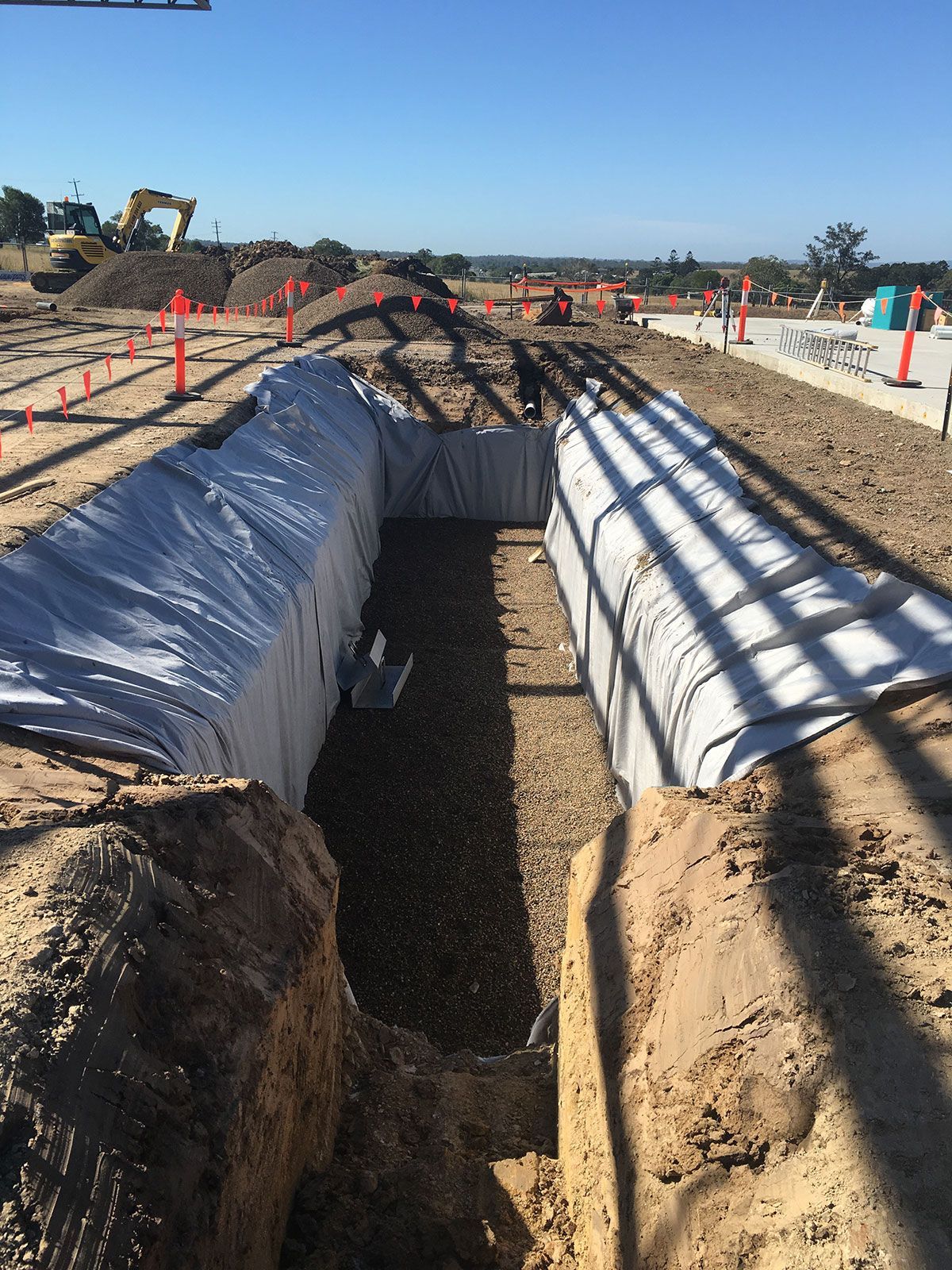 A large trench is being dug in the dirt on a construction site.