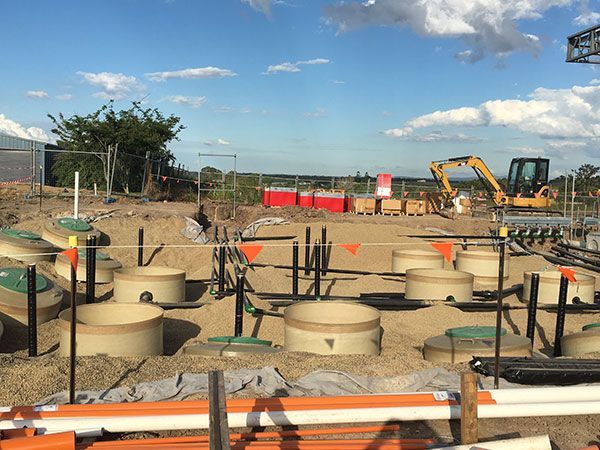 A construction site with a lot of pipes and a crane in the background.