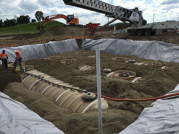 A large pile of dirt is being poured into a large hole.
