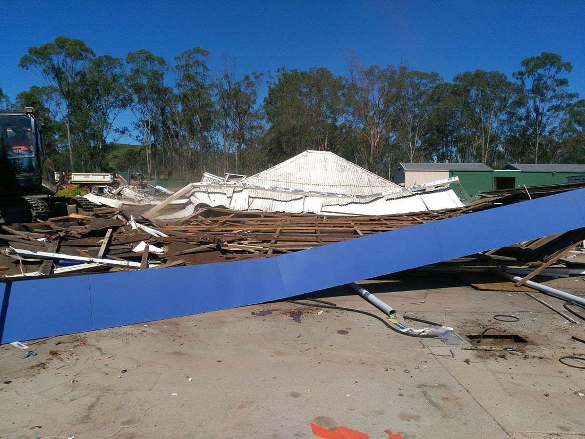 A blue tarp is laying on the ground in front of a pile of wood