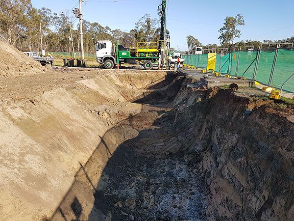 A large hole in the ground with a truck in the background