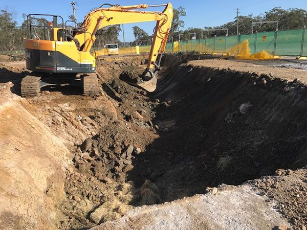 A yellow excavator is digging a hole in the ground