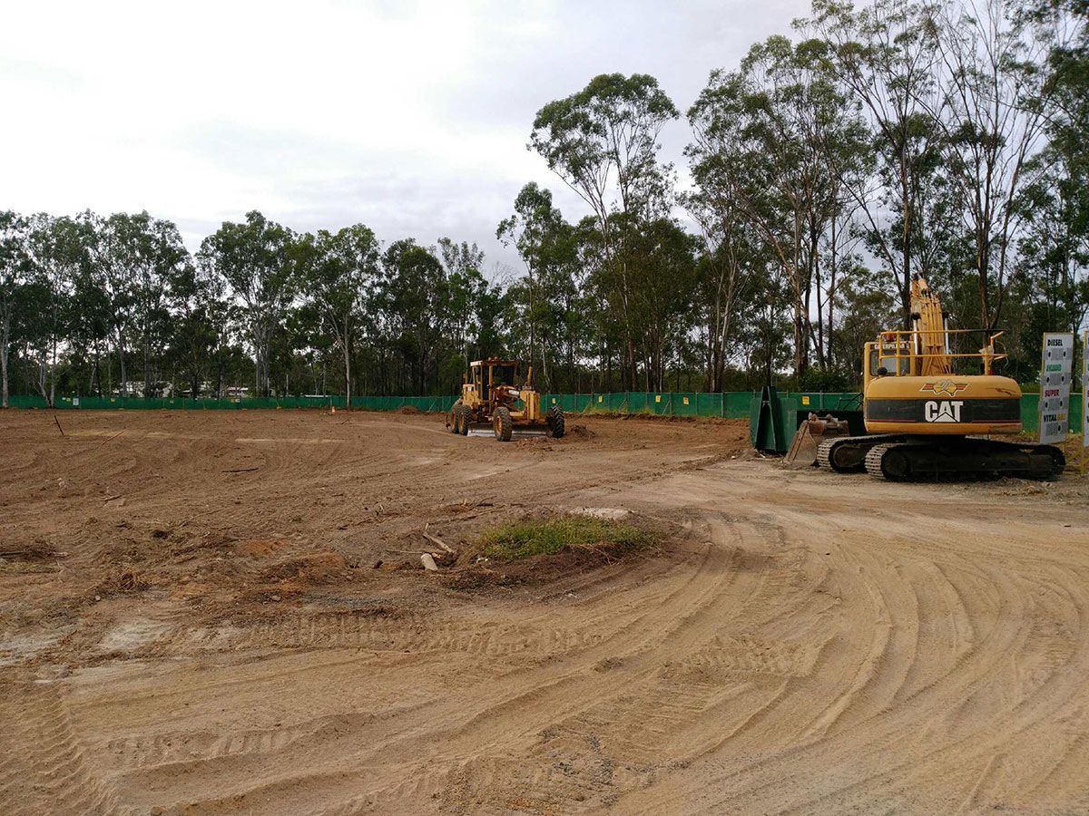 A construction site with a lot of dirt and trees in the background.